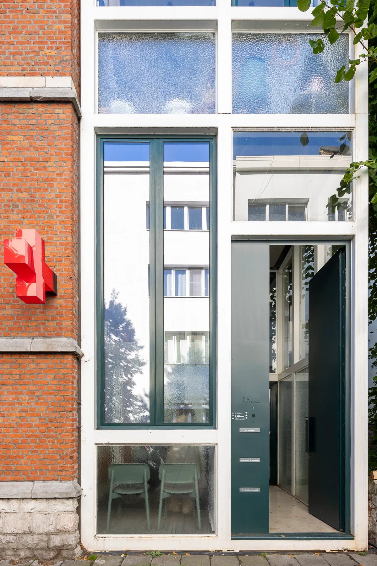 De ingang van Huisartsenpraktijk Badhuis: een groene deur naast het rode kruis aan de bakstenen gevel